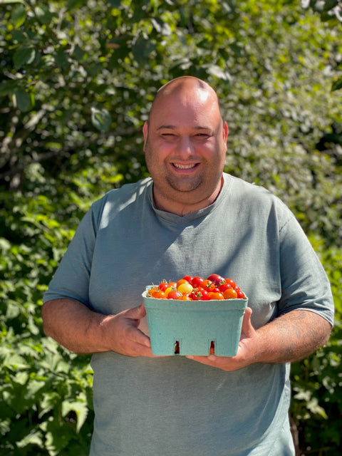 Tofino Ucluelet Culinary Guild's New Executive Director Rob Renna holding a box of fresh island grown tomatoes