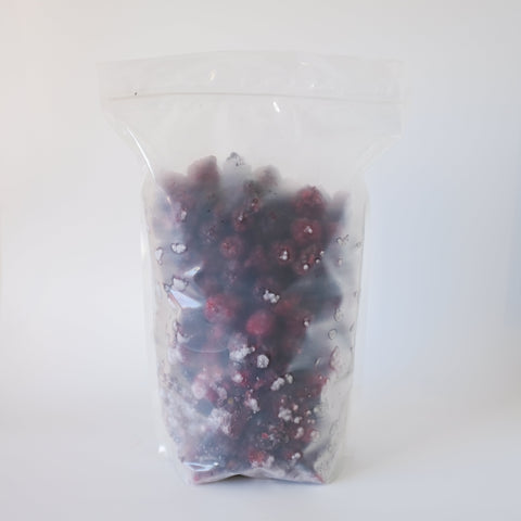 Clear plastic bag filled with blackberries on a white background