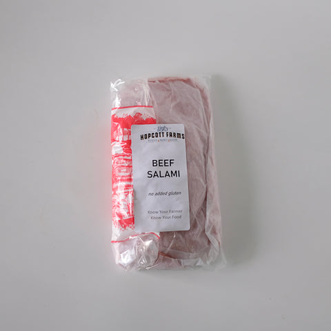 Packaged beef salami with a label on a gray background