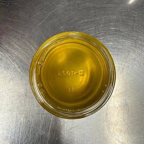 Small glass container with yellow liquid on a metallic surface