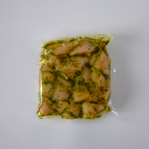 Packaged chicken with green seasoning on a white background