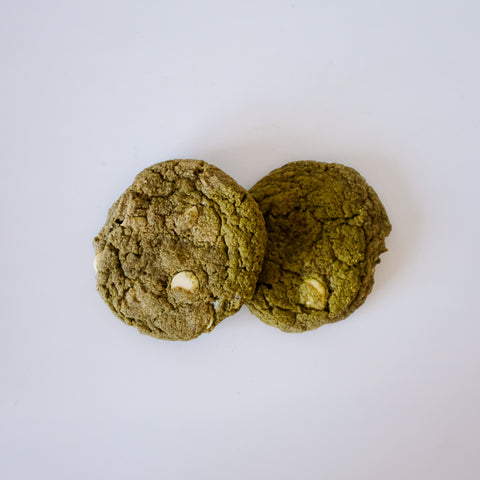 Two green cookies with white chips on a white background