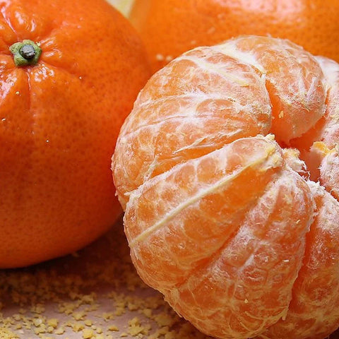 Close-up of a peeled orange with another orange in the background.
