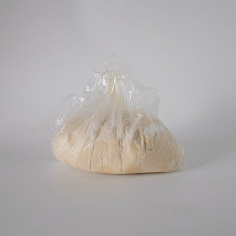 Ball of dough wrapped in plastic on a white background
