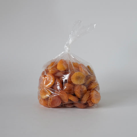 Clear plastic bag filled with dried apricots on a white background